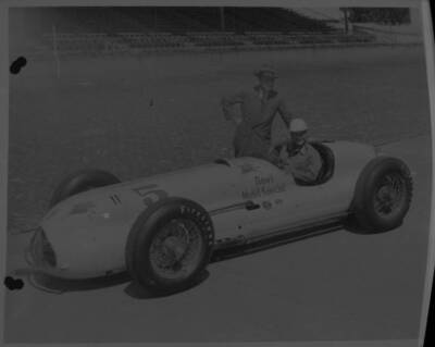 Rex Mays sits in the #5 Novi Mobil Special as another man stand 1949 Indy Photo