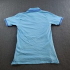 Light blue boys’ polo shirt with white sleeve trim, blue shirt buttons, and “Aston Martin Racing Team” logo on back.
