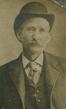 MAN, RELAXED STANDING POSE, SMOKING A CIGAR AND WEARING A BOWLER HAT. 