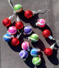 Lot of 16 round Christmas balls with multicolor horizontal stripes in red, red-green, and red-purple on a black background.