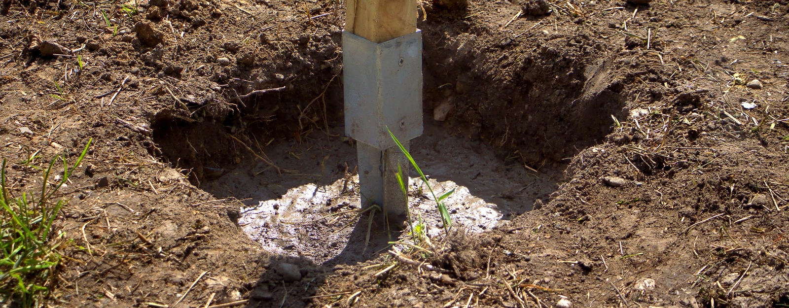 Eine Bodenhülse wird in einem Bodenloch einbetoniert.