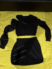 Womans black two-piece set, long-sleeve top with zippers and a skirt with zipper