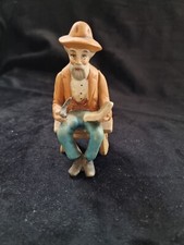 Old man on a bench reading smoking a pipe figurine