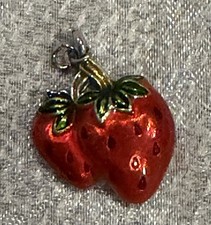 A strawberry-shaped charm or small pendant, featuring a vibrant red enamel