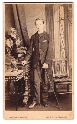 Fotografie Stuart Bros, London, 47 Brompton Road, Bursche im Anzug mit Gehstock 