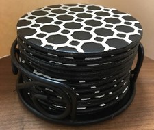 12 faux leather black circular coasters with raised white lattice in a stand