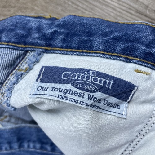Blue denim Carhartt men’s carpenter jeans, faded thighs, 44x30, white tag with logo and red “Our Toughest Work Denim” text.