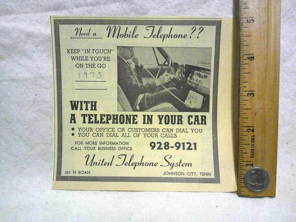 A 1973 vintage car phone clip — a proto-mobile phone accessory from an era when 'car phone' meant something truly ridiculous, perfect desk or shelf curiosity.