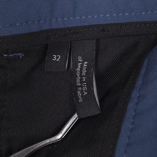 Black fabric tag on waistband of blue 32 slim fit THEORY men’s dress pants, reading “Made in U.S.A.”