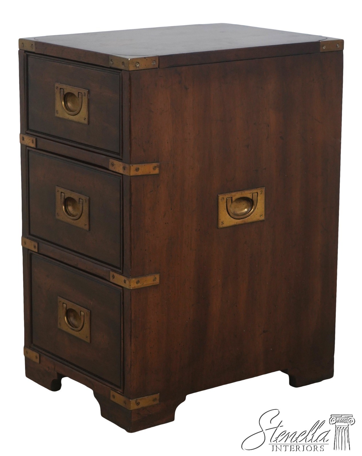 Small wooden campaign-style chest of drawers with brass corner hardware and drawer pulls.