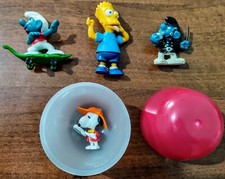 Lotto 4 Sorprese Kinder con Snoopy Bart dei Simpson e 2 Puffi + Custodia Uovo