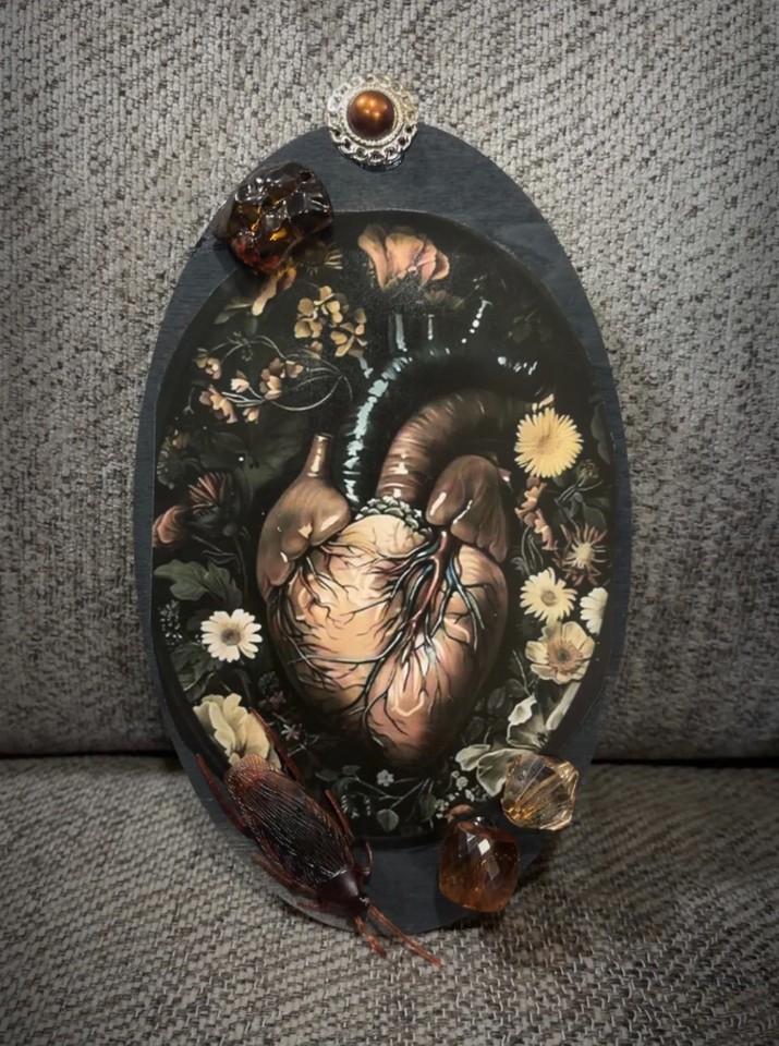 A one-of-a-kind handmade floral heart oddity wall plaque that mixes botanical prettiness with unsettling anatomical energy.