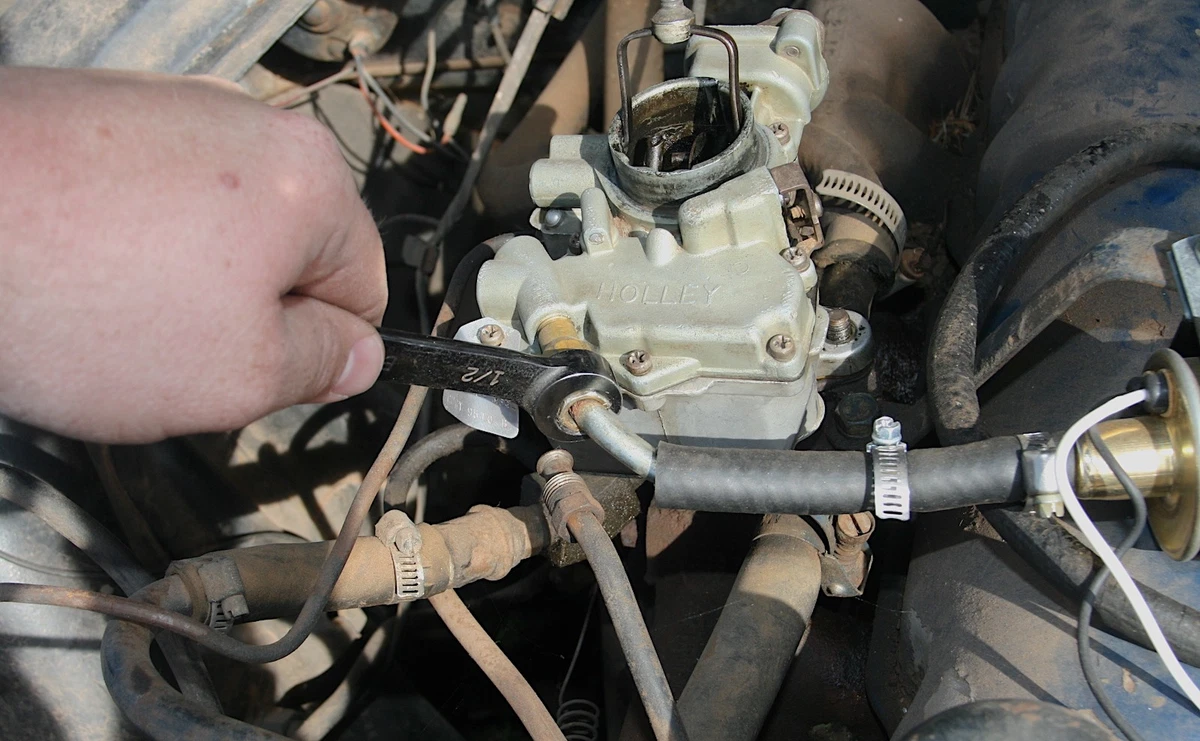 Use a line wrench to remove a fuel hard line before cleaning the carburetor.
