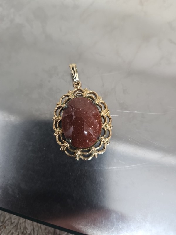 Vintage goldstone, set in an ornate gold-tone filigree frame.