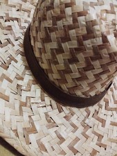 Cappello di paglia intrecciata con una fascia marrone.- Materiale: paglia.