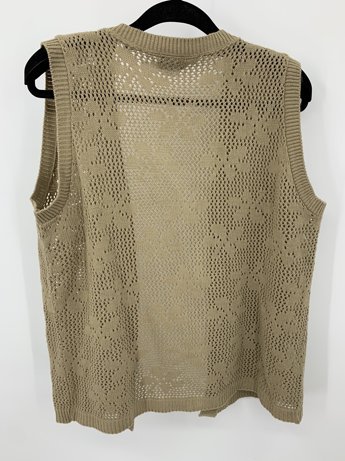 Beige open-front knit sweater vest with floral lace pattern and scalloped edges, displayed on black hanger.