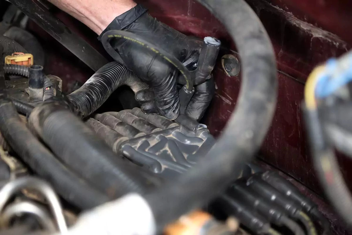A mechanic connects the ignition coil wire to the distributor.