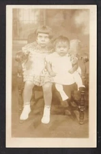 TWO CHILDREN SITTING ON CHAIR (RPPC)