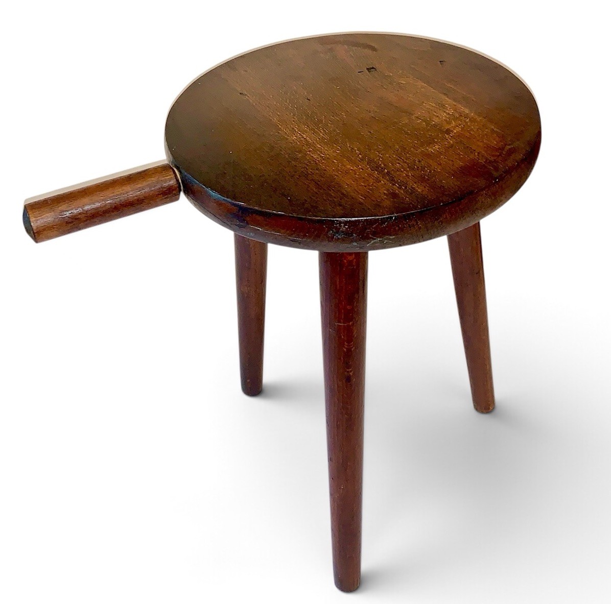 Three-legged wooden milking stool with a center carry handle.