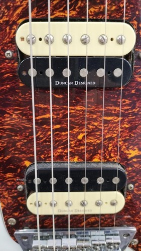 Black SQUIER VATAGE MOD Jager electric guitar with white pickguard, silver hardware, and orange-brown textured finish.