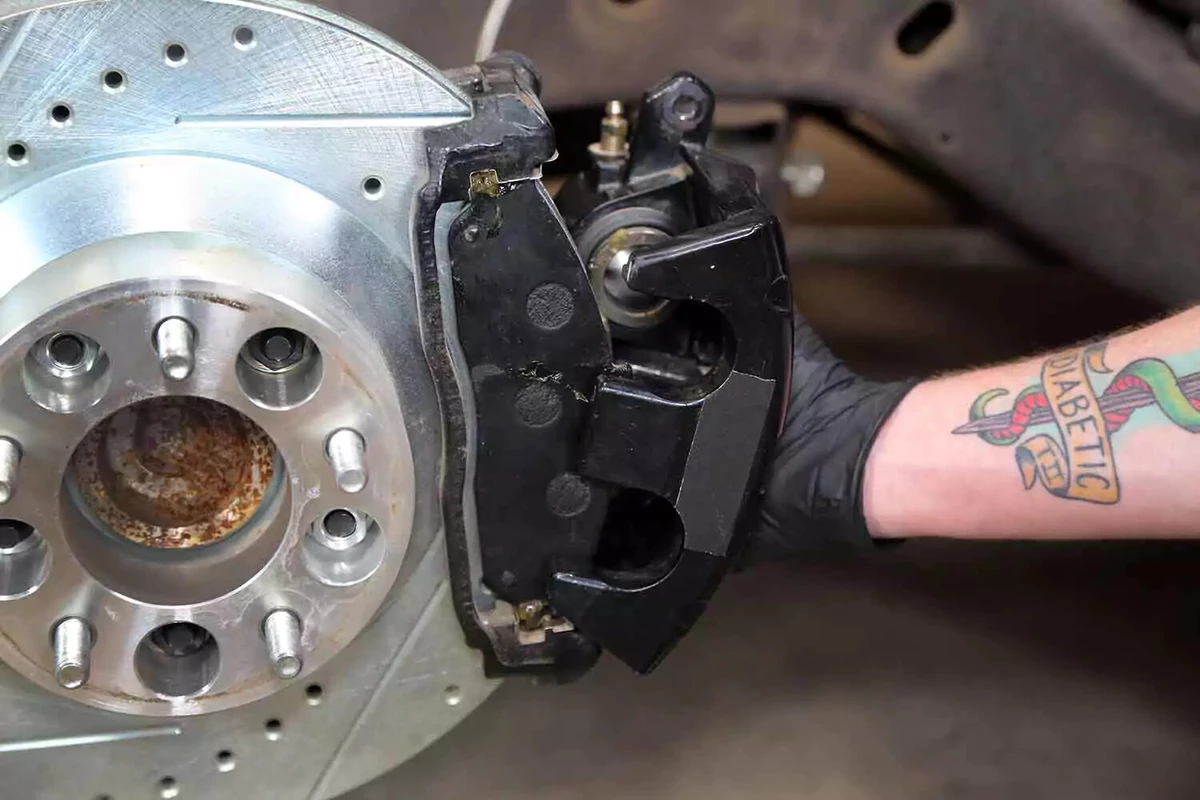 A mechanic slides the caliper over the brake pads.