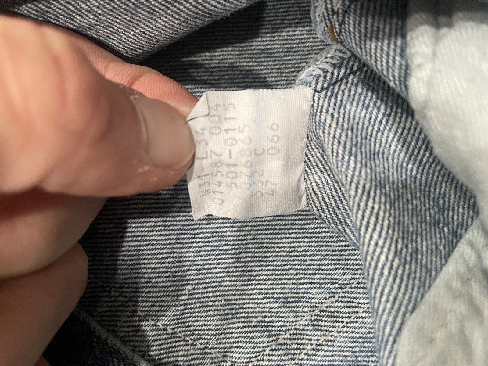 White vintage Levi’s 501XX Blue made in USA tag with green seal, showing size 31x34 and product details on fabric.