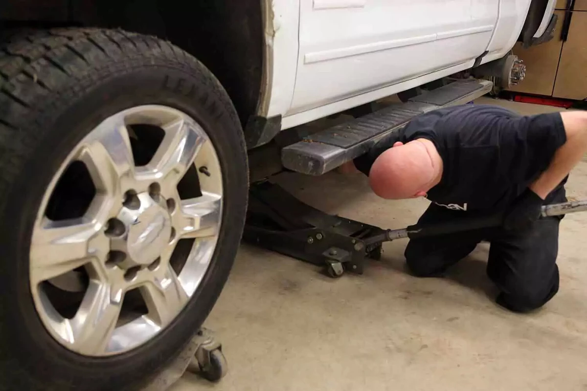 A mechanic raises the floor jack in order to remove the jack stand.