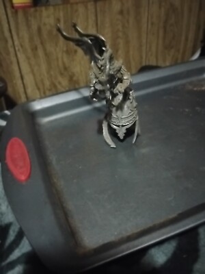 This Is a pewter figurine of a dragon perched on a Roman helmet.