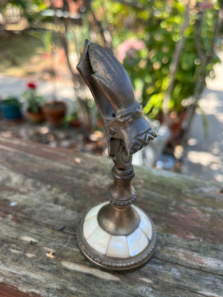 A Victorian brass hand letter clip with mother-of-pearl inlay — an absurdly elegant little artifact that makes holding paper feel like a ceremony.