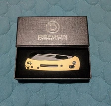 DEF CON AXIS LOCK BRASS ANODIZED HANDLE BLACK D2 BLADE.