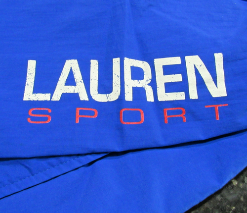 Blue fabric Ralph Lauren Sport jacket with white “LAUREN SPORT” text and red stripe, USA made size A–XL.