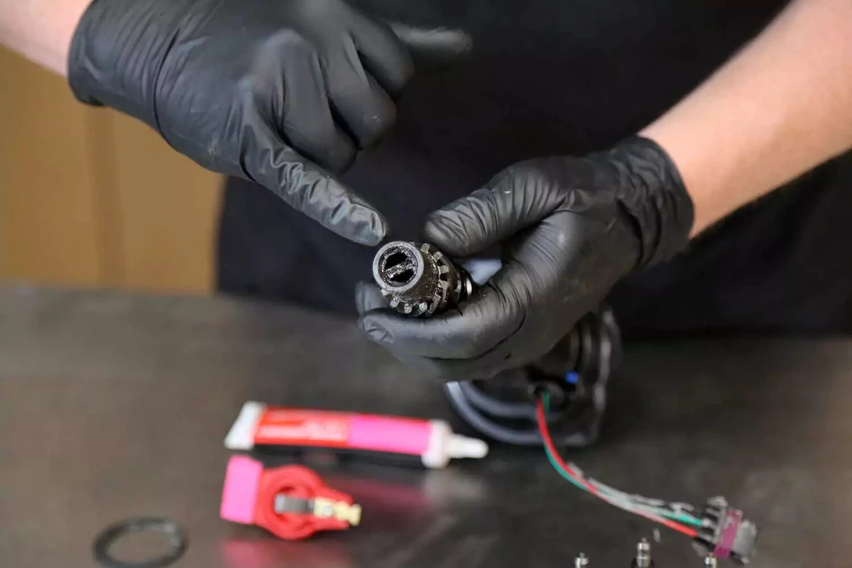 A mechanic points out the gears on the bottom end of the distributor.
