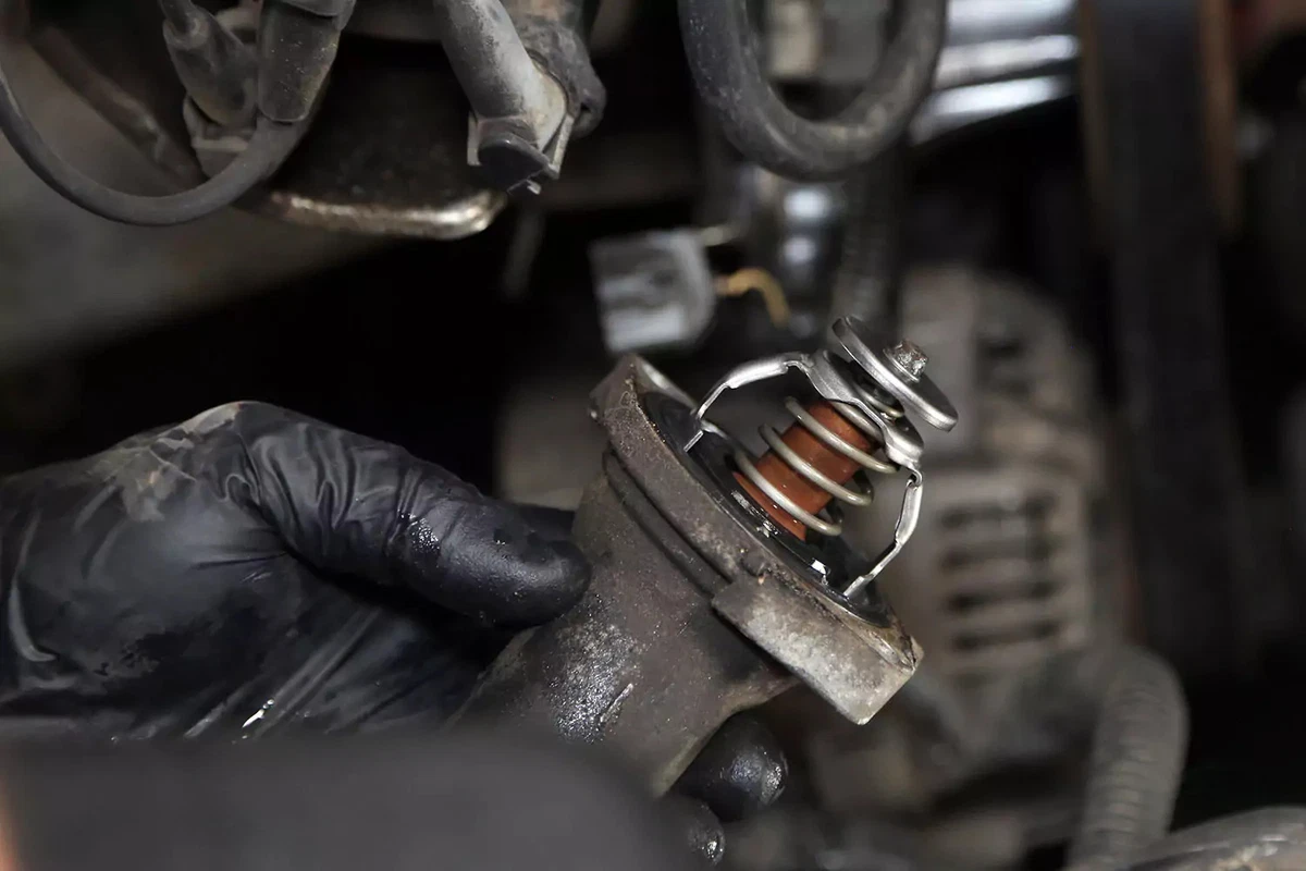 Mechanic holding the water neck with the old thermostat still in place.