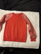 Extremely Me red crewneck sweatshirt with silver leopard-print sleeves.