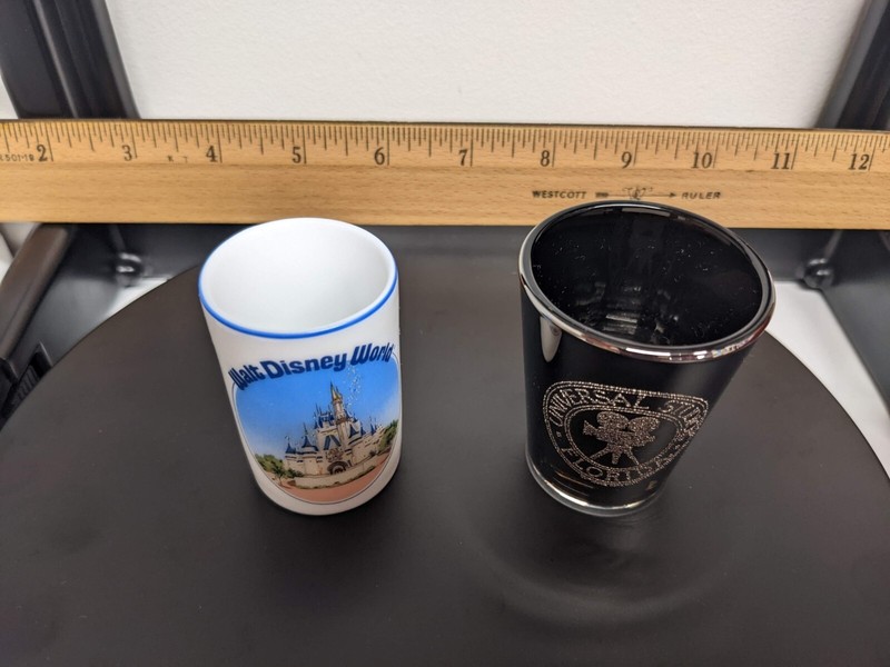 Disney white Cinderella's castle and Universal Studios black shot glass lot of 2