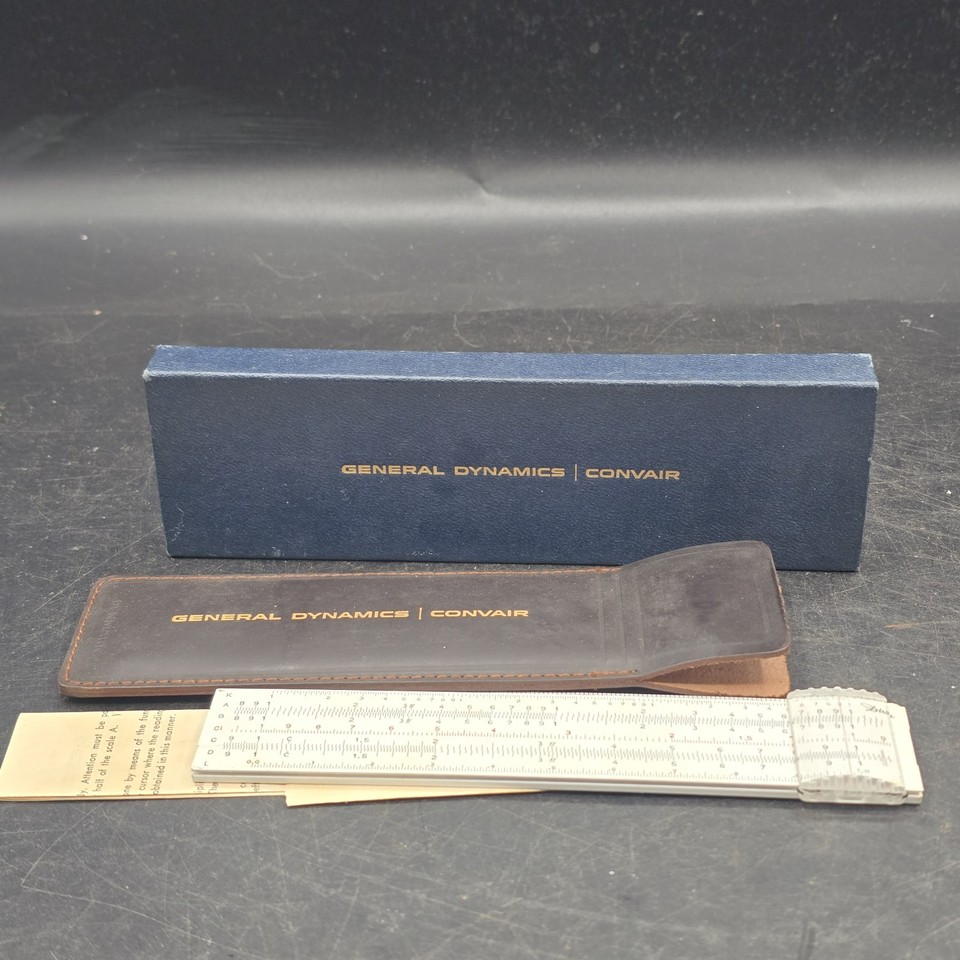 A never-used slide rule branded for General Dynamics — a piece of Cold War corporate engineering history still in its original box, straight from a defense contractor's desk drawer.