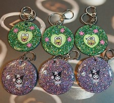 2in Round Acrylic Keychains with glitter, Keroppi an Kuromi characters on them.