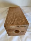 Rectangular solid honey oak wood knife storage block with 13 slots and a central circular hole on a white fabric surface.