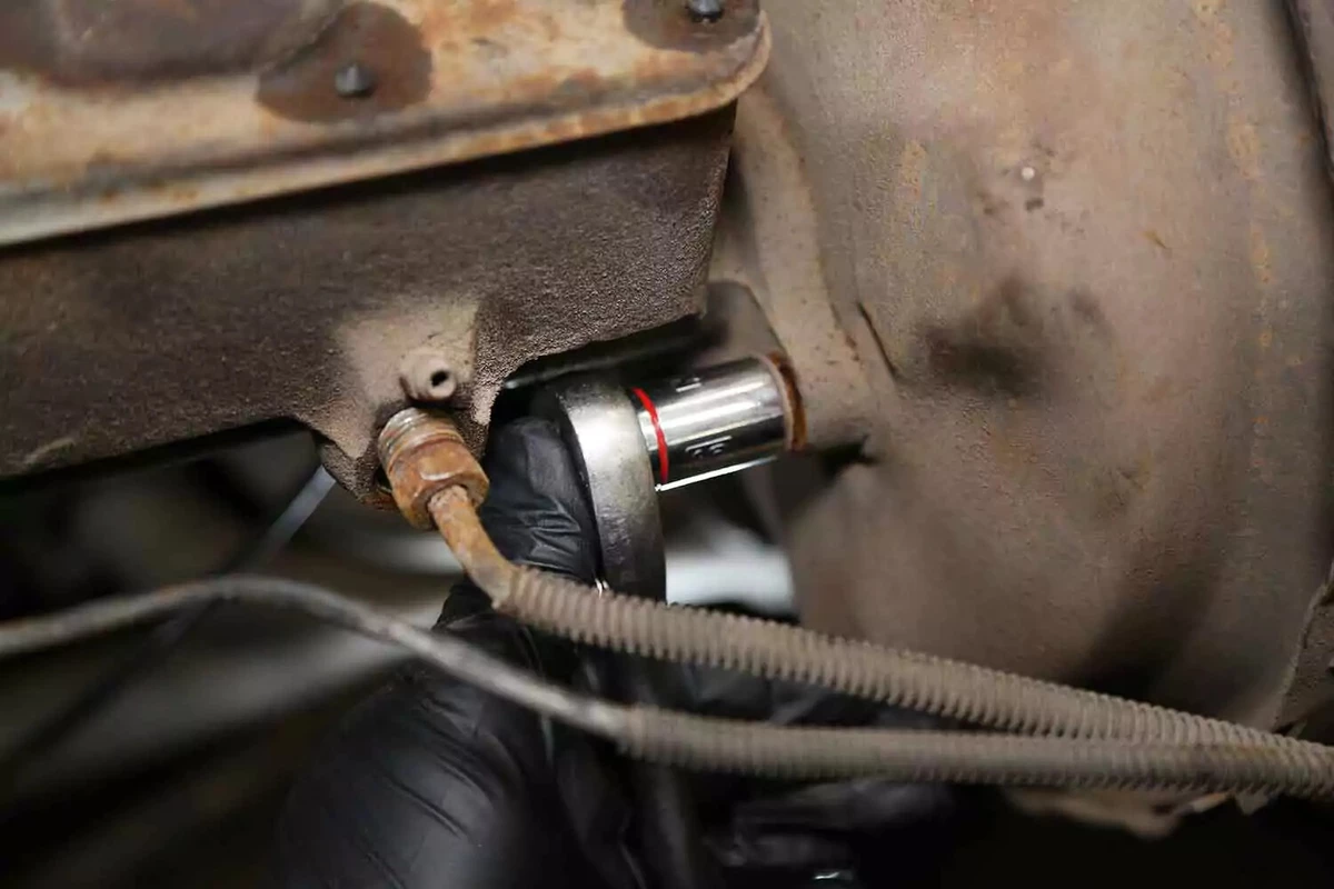 Using a socket to loosen and remove the nuts connecting the master cylinder to the brake booster.