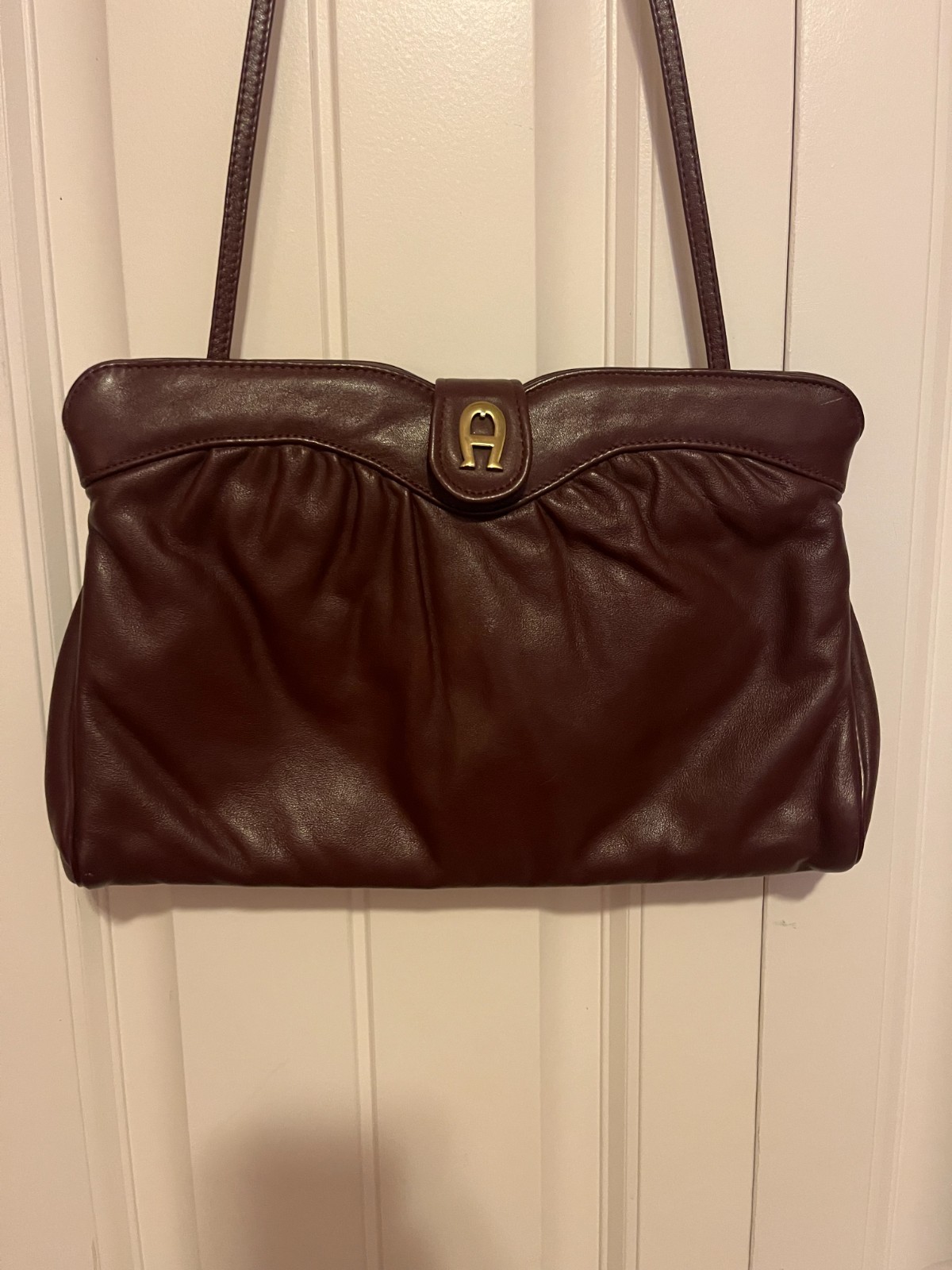 Oxblood leather shoulder bag with brass Etienne Aigner clasp and long strap.