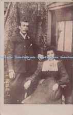 R697009 Woman Sitting in a Chair. Man is standing nearby in a Suit