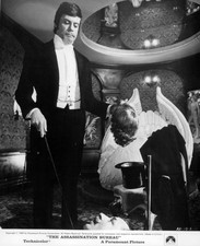 Oliver Reed standing holding a wig poking Telly Savalas with a sti- Old Photo