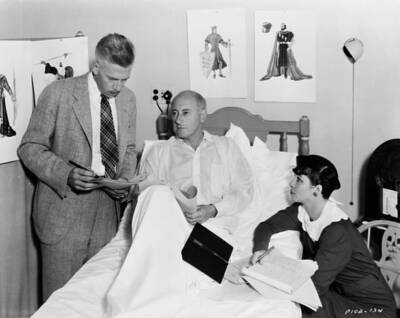 Filmmaker Cecil B DeMille recuperating in bed as his staff discuss- Old Photo