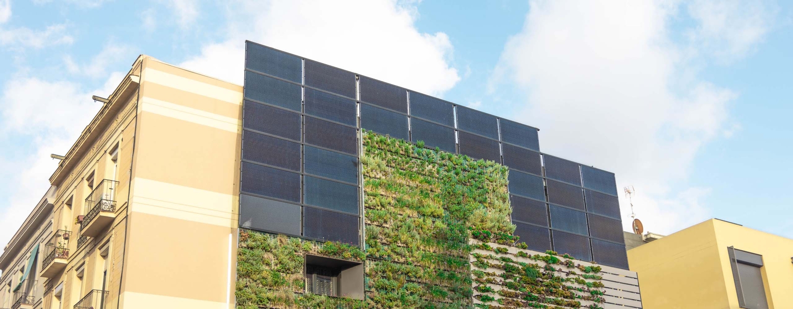 Ein modernes Gebäude mit einer begrünten Fassade und Solarpaneelen