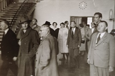 Gruppenfoto Frauen und Männer in Mänteln stehen im Treppenhaus Treppe Uhr Foto
