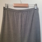 Grey maxi skirt with vertical tiered flowy panels, elastic waistband, and straight hem, hanging on a wooden hanger.