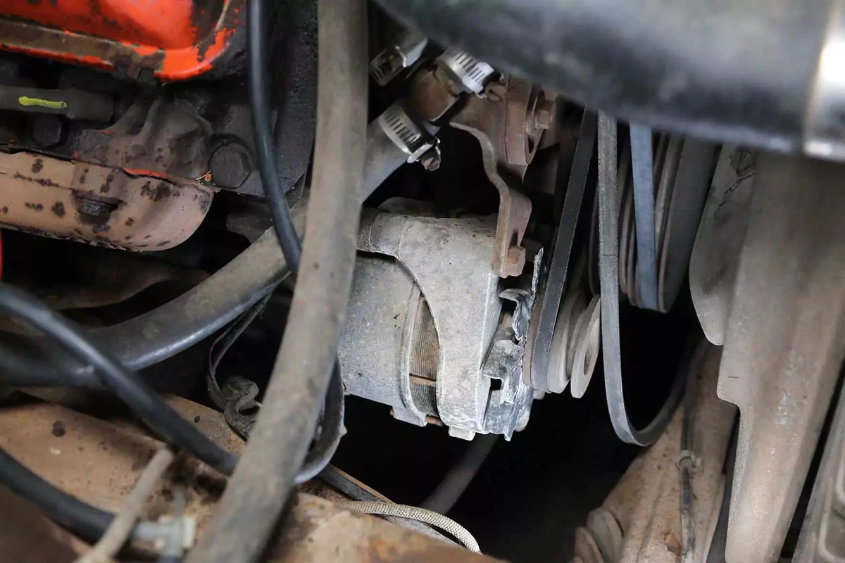 A vehicle’s alternator and V-belts in the engine bay.