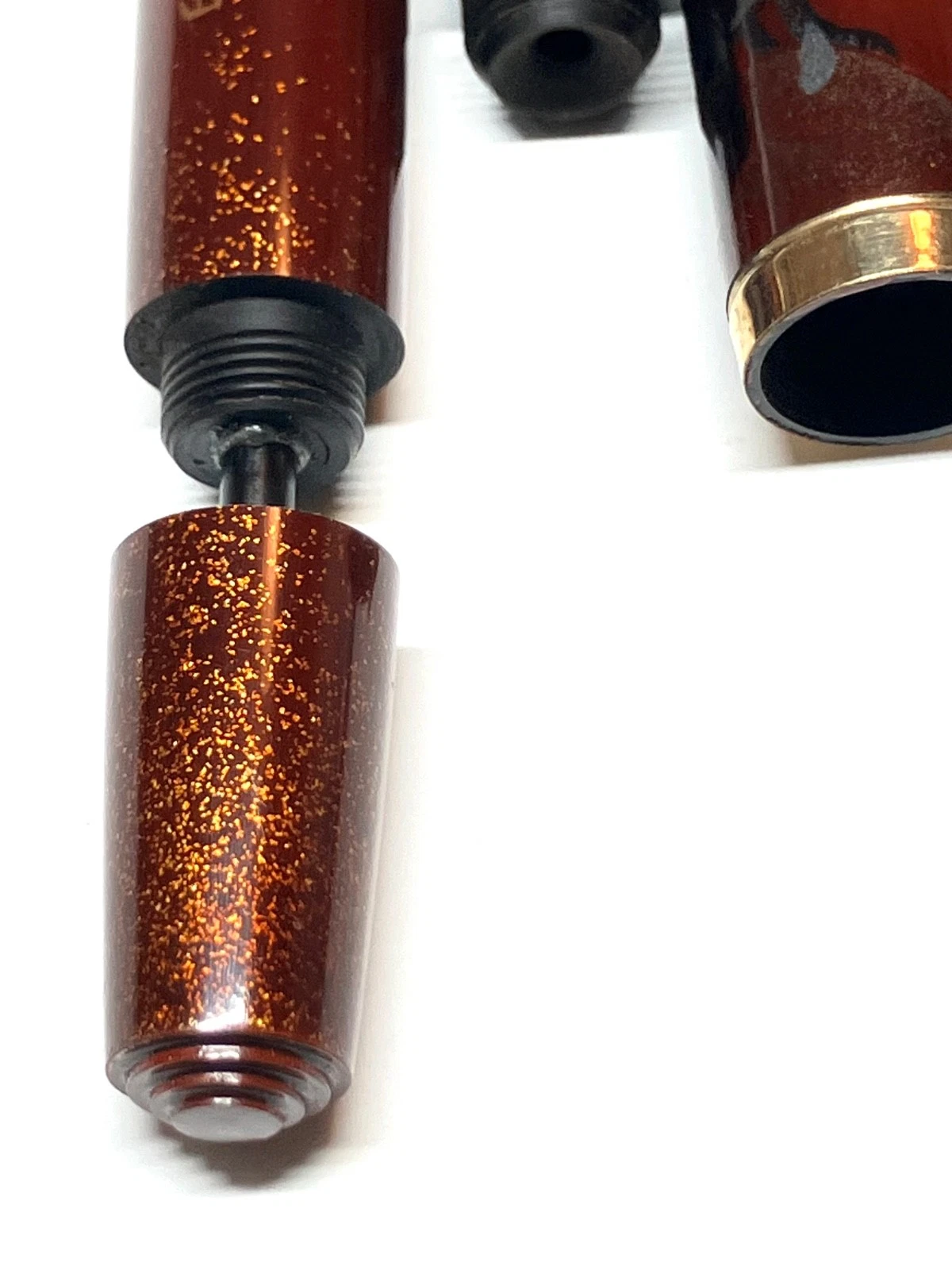 Vintage ink shut off fountain pen with brass section, black ink reservoir, and orange-brown barrel with gold lettering.