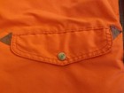 Orange cotton-nylon Perfecto parka with front snap pocket, flap pockets, and triangular stitched accents.