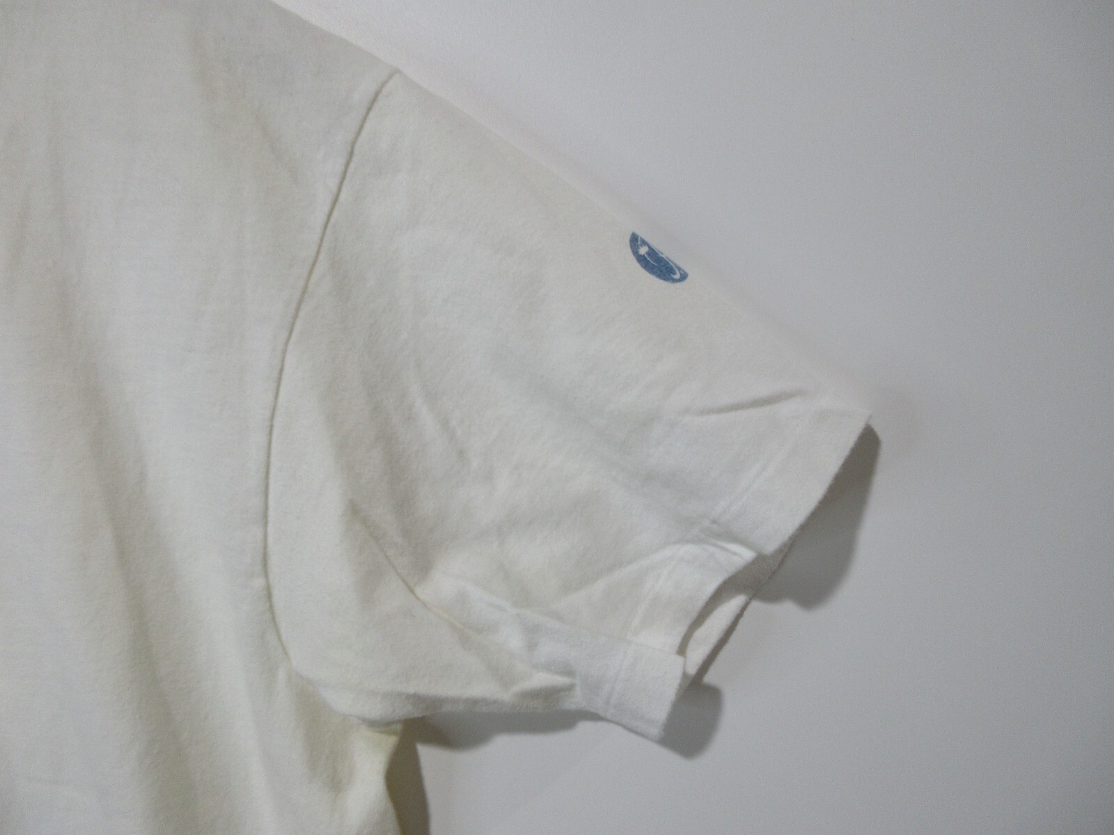 Light gray long-sleeve shirt with a blue ink round patch on the left sleeve, white club Newport cotton.